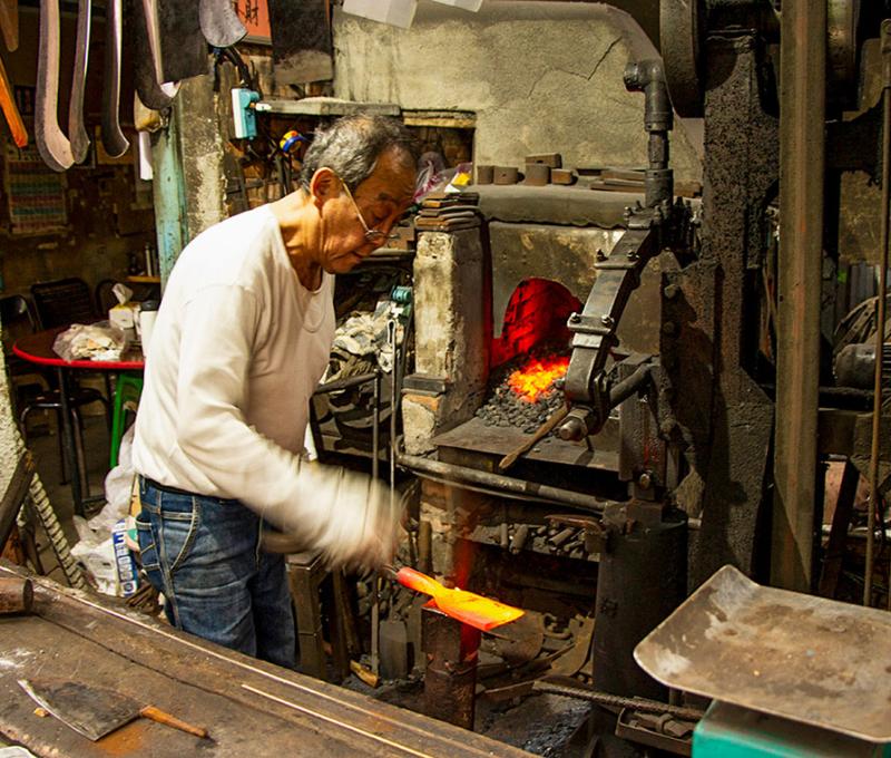 開了爐具，頂著高溫，為居民維修農具。